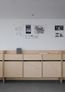 A professional office space with pinned architectural plans and books on the wall