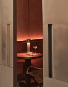 A dimly lit room with a wooden table, wine glasses, and a bottle of wine, surrounded by chairs in a relaxing and intimate atmosphere