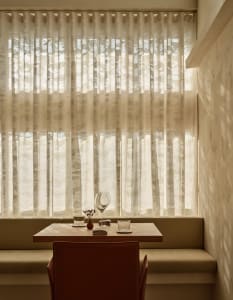 A cozy dining area in a restaurant with a wooden table, wine glasses, and cups, set in a warm and inviting atmosphere