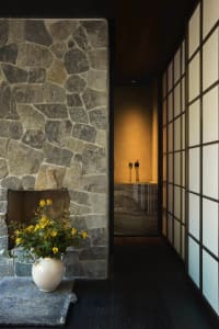 Cozy bathroom with a stone wall, a vase with yellow flowers, a bathtub, and two bottles