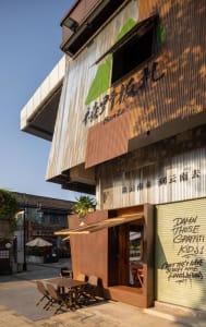 Rustic cafe interior with a blend of traditional and modern elements, featuring wood and metal accents, potted plants, and dining tables and chairs