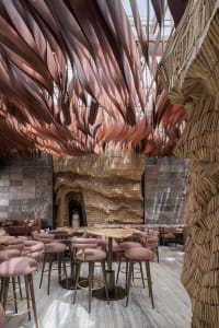Modern restaurant interior with wooden walls, tables, chairs, and bar stools, creating a warm and inviting atmosphere