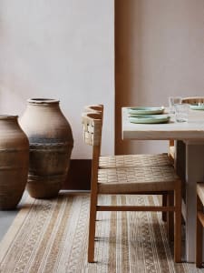 Cozy dining space with a wooden table, chairs, and a pink wall, suggesting a warm and inviting atmosphere