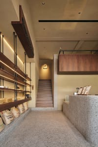 A commercial staircase with wooden steps and bags on the ground, set in a building with a service-oriented atmosphere