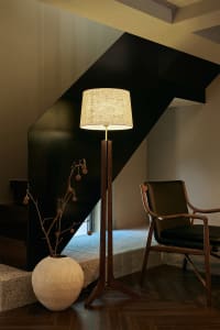 Cozy interior space with a black staircase, two chairs, a lamp, and a potted plant