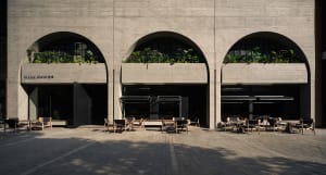 Architectural scene of two buildings with large arches adorned with greenery, featuring chairs and potted plants
