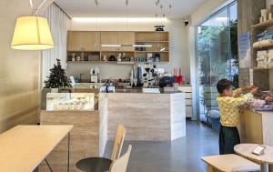 A cozy cafe with a counter and seating area, featuring cups and bottles, and an inviting atmosphere