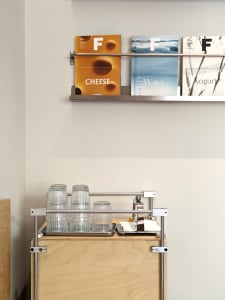 A casual kitchen scene with a bookshelf, books, cups, and a bottle, set in a warm and inviting atmosphere