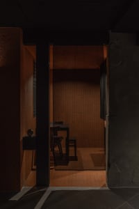 A dimly lit dining room with a table and chairs, tile-adorned walls, and a cozy atmosphere