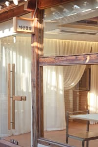 Warm and inviting Asian restaurant interior with a wooden door, window, and chairs around two dining tables