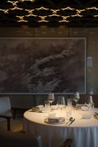 A luxurious dining area with a large table set for a meal, surrounded by chairs, wine glasses, and fine china