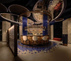 A well-designed bar area with a round counter and multiple chairs, featuring a variety of bottles and a cozy atmosphere
