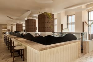 A modern restaurant bar with a black countertop, white walls, and comfortable seating around a dining table