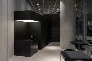 Dark office interior with a black countertop, a large window, and two chairs, lacking natural light