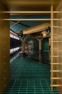 Luxurious bathroom with green tiles, two large columns, and well-lit interior