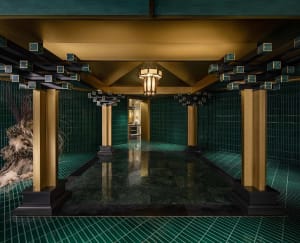 Ornate bathroom with a large tiled floor featuring a checkered pattern in green and gold tones, adorned with gold accents and intricate patterns