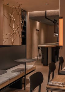 A modern cafe dining area with wooden walls, several chairs, and two tables, creating a warm and inviting atmosphere with clean lines and minimalistic decoration