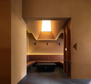 Modern room with orange walls, brown benches, and natural light from a large window