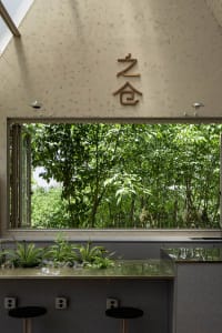 Asian-inspired bathroom with a large window, sink area, and potted plant, featuring natural light and a serene atmosphere