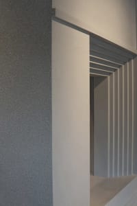 Interior space with a white doorframe and gray wall, open doorway revealing a hallway beyond, clean and minimalist design