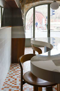 A cozy restaurant interior with a marble counter and three chairs, creating a welcoming atmosphere for dining