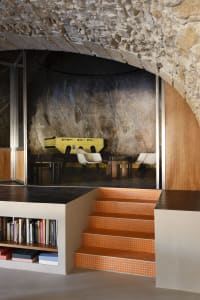 A well-lit dining area with a table and chairs, surrounded by a bookshelf and natural or artificial light sources