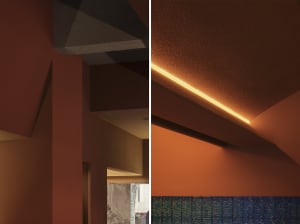 Warm and inviting living space with orange walls, a red accent wall, a stone accent wall, a dining table, chairs, and a kitchen sink