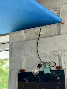 A blue curtain hangs on a brick wall with two old-fashioned lights attached, creating a unique interior design concept