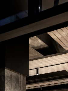 A large open space with a high ceiling, featuring concrete and metal elements, and possibly natural or artificial light sources