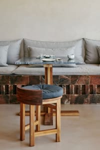 A warm and inviting living space with a stone wall, a couch, a dining table, and two chairs, with various items on the table suggesting recent meals