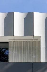 A modern building with a curved design and glass facade, featuring a bright and airy interior with natural light
