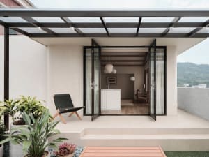 Open concept living area with a large window, kitchen, dining table, and comfortable seating, featuring natural light, decorative elements, and a sense of comfort and functionality