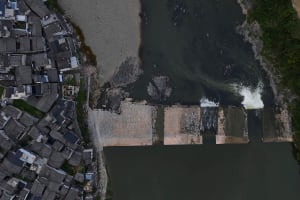A cityscape with a dam constructed from concrete, surrounded by buildings and a body of water