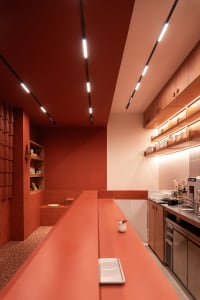 A modern kitchen with red walls, orange countertops, a dining table, chairs, appliances, and multiple cups on the countertops