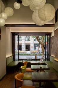 Modern restaurant interior with wood paneling, tables, chairs, and potted plants, creating a warm and inviting atmosphere