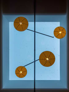 A dimly lit room with three lights hanging from the ceiling at different heights and angles, creating a unique design element