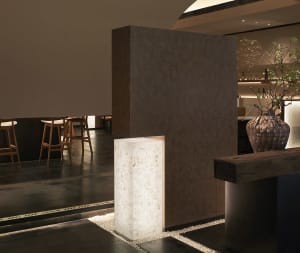 Elegant modern room with a stone wall, two chairs, and a dining table, featuring natural materials and a sophisticated atmosphere