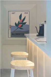 Inviting coffee shop interior with a wooden counter, a poster on the wall, and a sink in the background, featuring two cups and a comfortable atmosphere