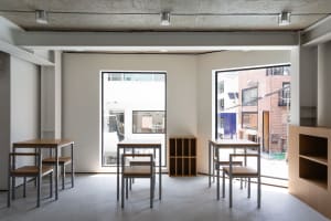 Empty classroom with white walls, multiple tables, and chairs arranged for educational purposes