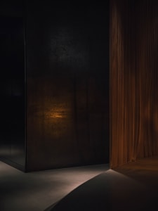A black doorway with an orange curtain in front of it, set against a stone wall, creating a warm and inviting atmosphere