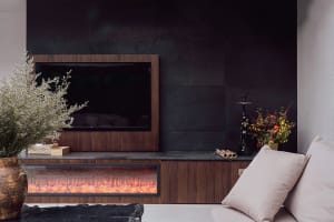 Modern living room with a flat screen TV, wooden furniture, a black fireplace, and inviting atmosphere