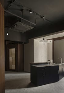 Empty kitchen with cement block walls, a sink, countertop, and cabinets, with a bottle on the counter