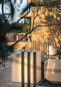 An inviting outdoor seating area with two central poles, well-lit and furnished with chairs and dining tables