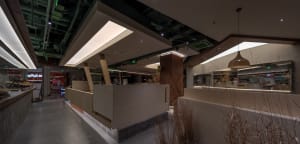 A warm and inviting indoor space with wooden floors and walls, featuring a living area and kitchen, with multiple people engaging in various activities