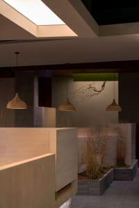 A modern living and dining area with a dining table, chairs, and hanging lights creating a warm atmosphere