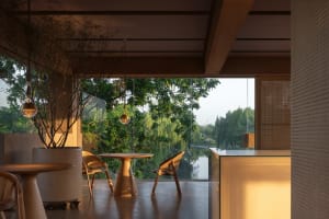Open living area with a dining table, couch, chairs, and wooden walls, featuring large windows for natural light