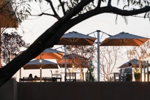 An outdoor dining area at night with multiple tables and chairs under umbrellas, creating a cozy and inviting atmosphere for guests to relax and socialize
