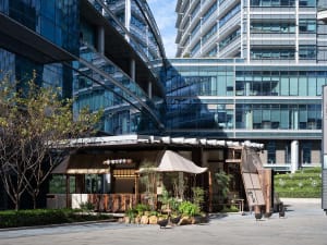 Modern open space with a glass facade, a dining table, and chairs, lit by natural light through the windows