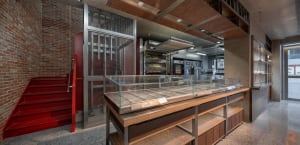 Industrial kitchen with glass display case, multiple ovens, and a professional atmosphere