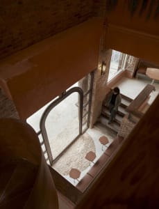 Cozy interior space with a brick building, a staircase, a dining table, chairs, and benches, with a warm and inviting atmosphere